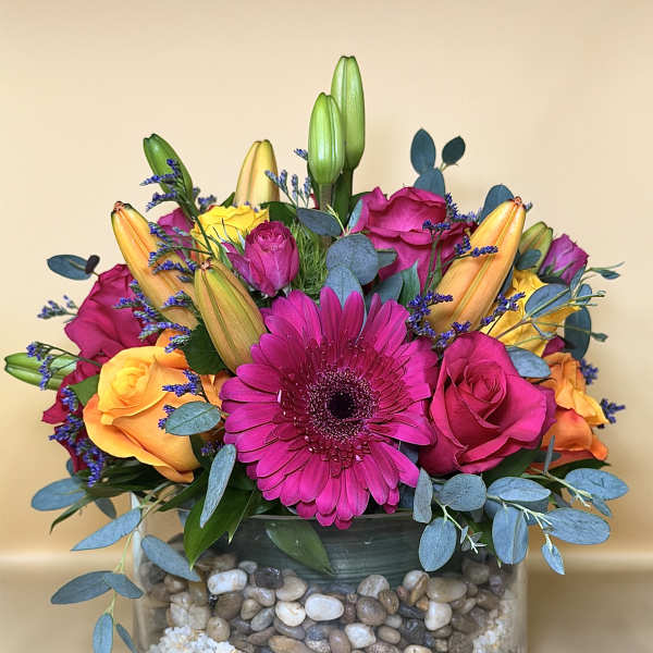 Bright mixed bouquet with pink gerbera, roses, and lilies in a glass vase