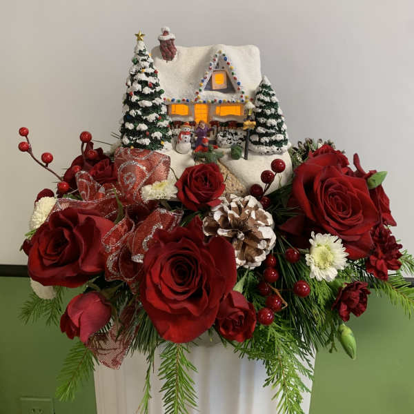 Christmas floral arrangement with red roses and a snowy house decoration