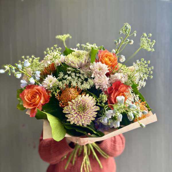 Hand-tied bouquet of orange roses and pale chrysanthemums with airy filler flowers