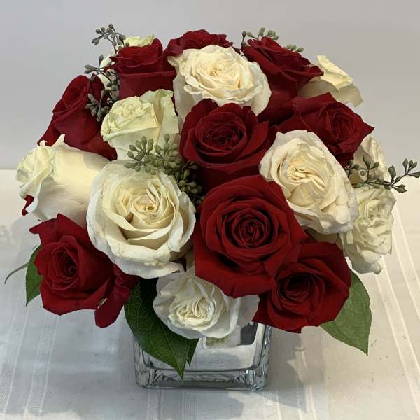 Red and white roses arranged in a clear square vase