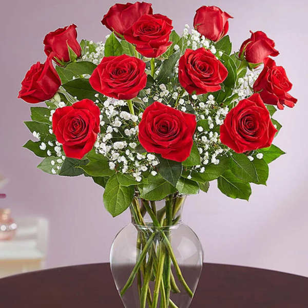 Arrangement of red roses with white filler flowers in a clear glass vase