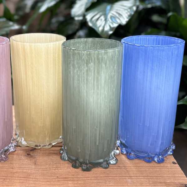 Four colored glass candle holders on a wooden surface