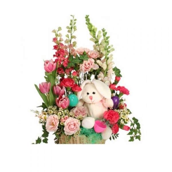 Basket arrangement with pink flowers and a plush bunny