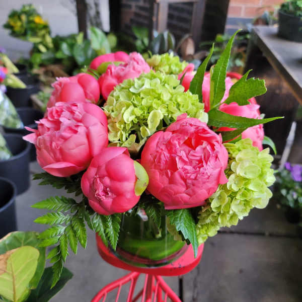 Pink peonies and green hydrangeas arranged in a glass vase
