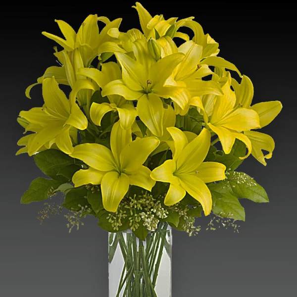 Yellow lilies arranged in a clear glass vase