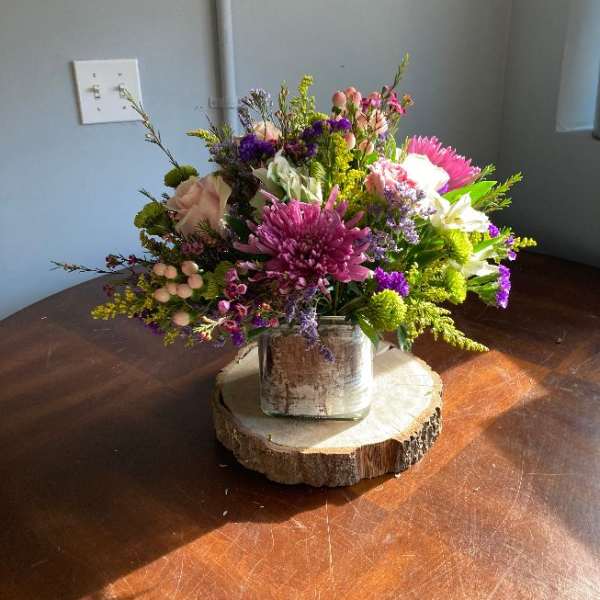 Mixed bouquet in a rustic square vase on a wood slice base