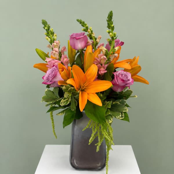 Orange lilies and pink roses in a dark vase