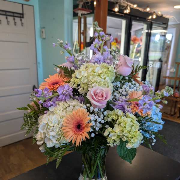 Mixed pastel bouquet in a clear glass vase with roses, hydrangeas, and gerbera daisies