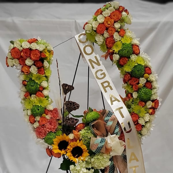 Floral wreath with orange and white roses, sunflowers, and a congratulatory ribbon