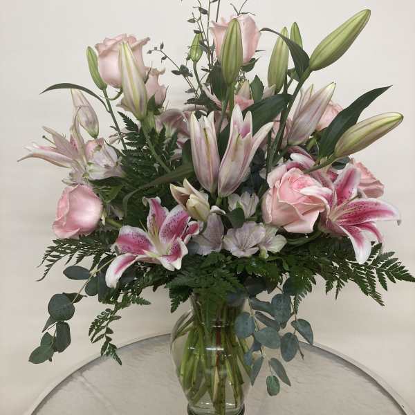 Pink roses and lilies arranged in a clear glass vase