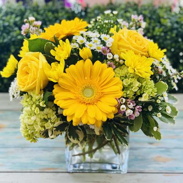 Yellow roses and daisies arranged in a clear glass vase