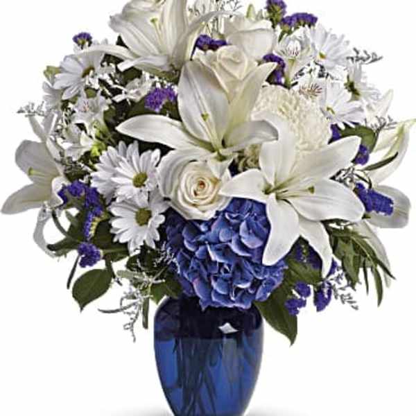 White lilies and daisies with blue flowers in a blue vase