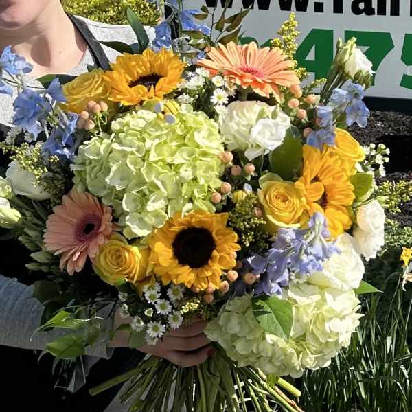 Handheld bouquet with sunflowers, roses, hydrangeas, and gerbera daisies