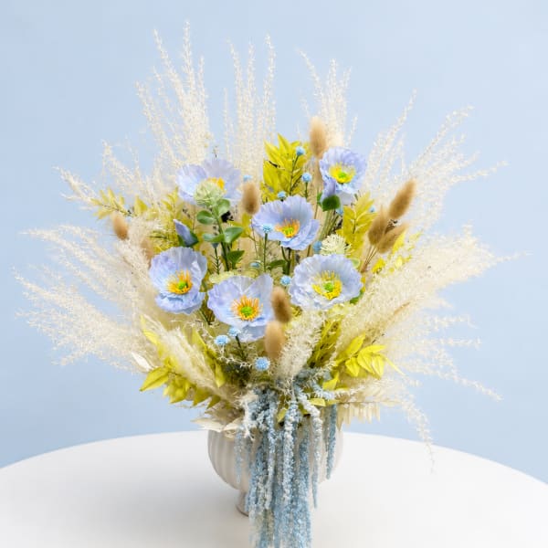 Tall pastel bouquet with blue flowers and dried grasses in a white vase