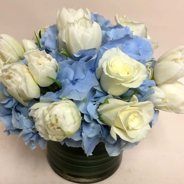 White roses and blue hydrangeas arranged in a dark green vase