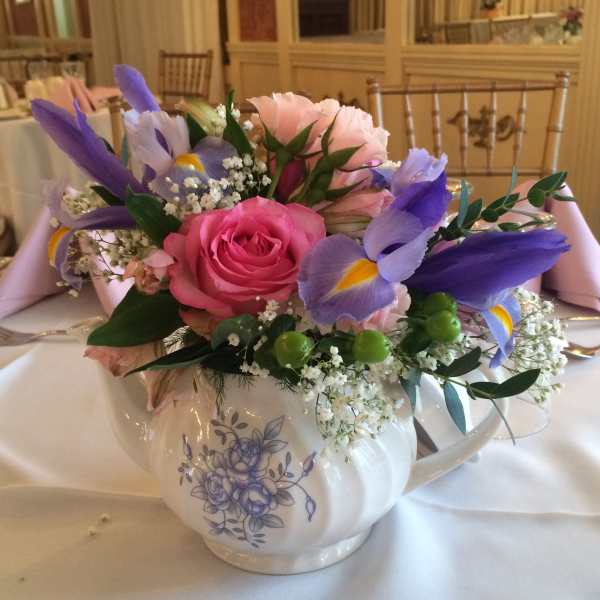Pink and purple floral arrangement in a white teapot vase