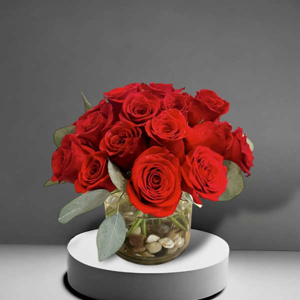 Red roses arranged in a glass vase with stones