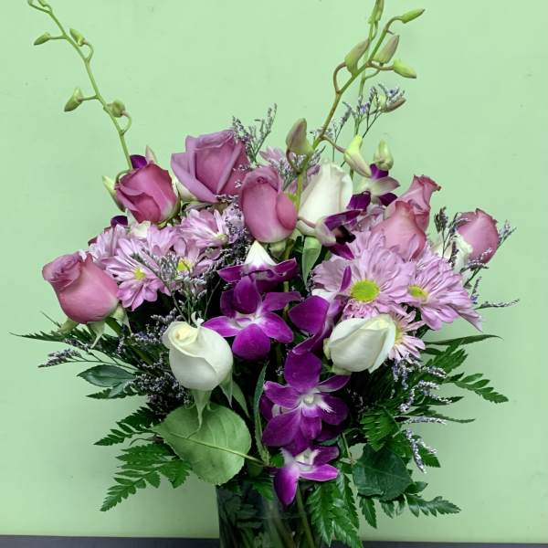 Pink roses and purple orchids in a glass vase