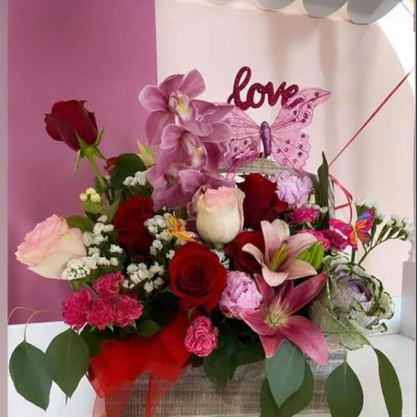 Pink and red flower arrangement with a love sign and butterfly decoration