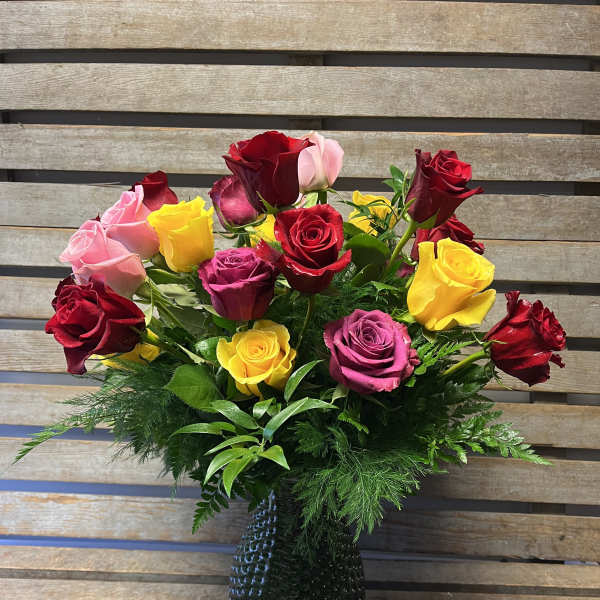 Mixed roses in red, pink, and yellow arranged in a dark vase
