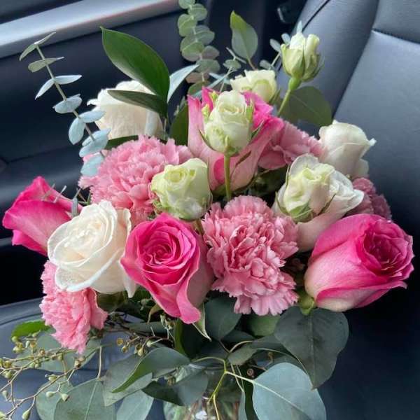 Pink and white rose bouquet with carnations in a glass vase