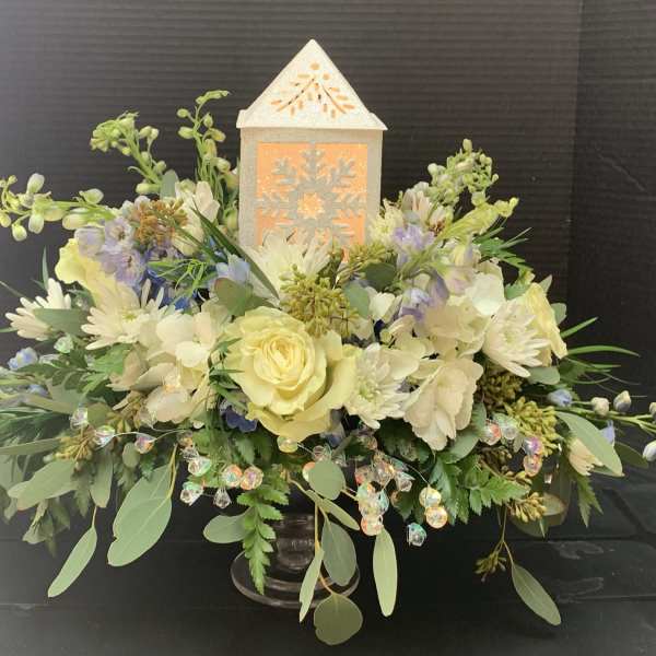 Cream and pale yellow floral arrangement with a lit lantern centerpiece