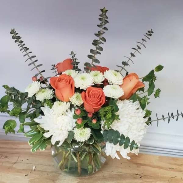 Orange roses and white chrysanthemums in a glass vase with eucalyptus