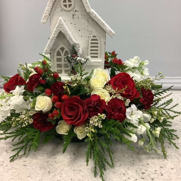 Red and white floral arrangement around a small white church decoration