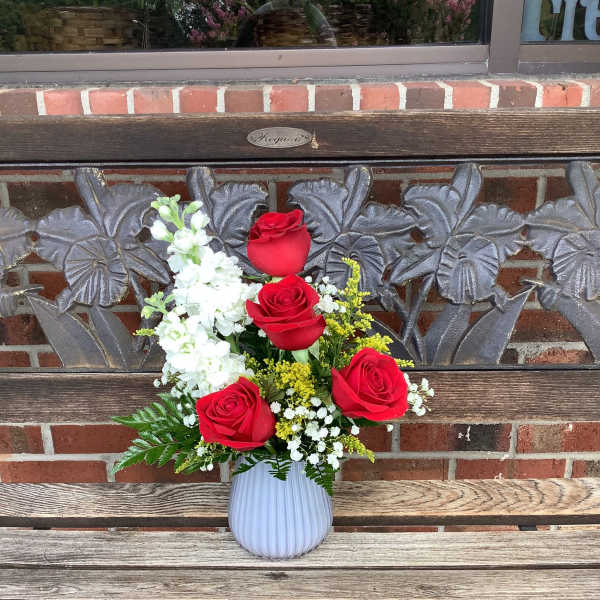 Red roses and white flowers in a white vase