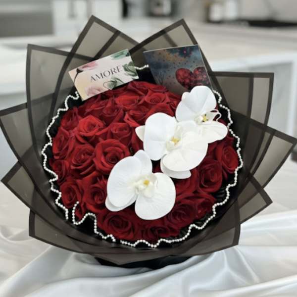 Bouquet of red roses with white orchids and dark wrapping
