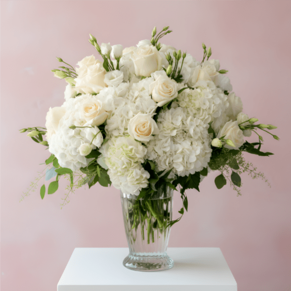 White roses and hydrangeas arranged in a clear glass vase