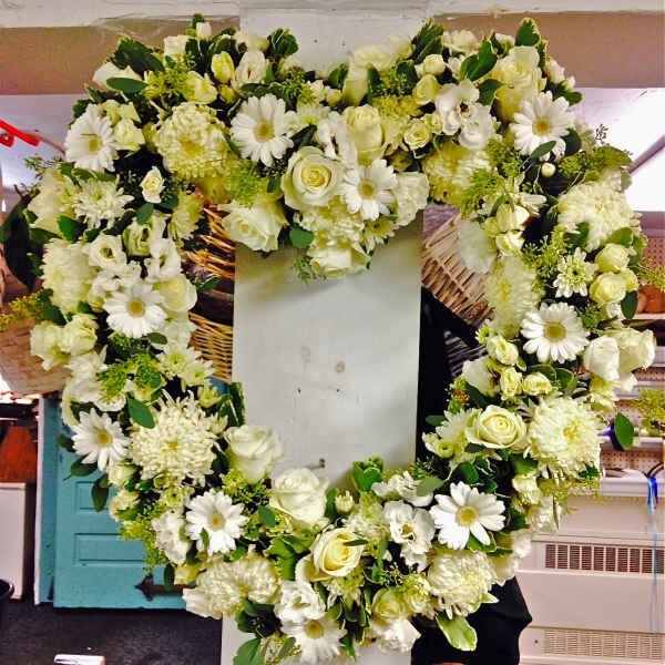 Heart-shaped white floral wreath on a stand