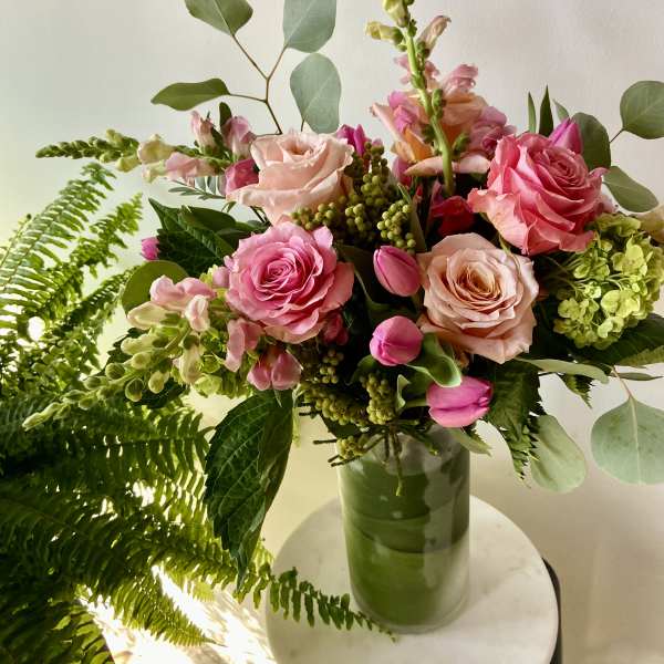 Pink roses and snapdragons in a green glass vase
