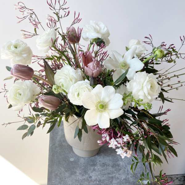 White and blush floral arrangement in a beige vase