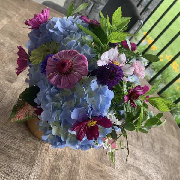 Bouquet of blue hydrangeas and purple daisies with greenery