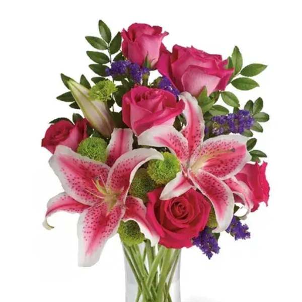 Pink roses and lilies arranged in a clear glass vase