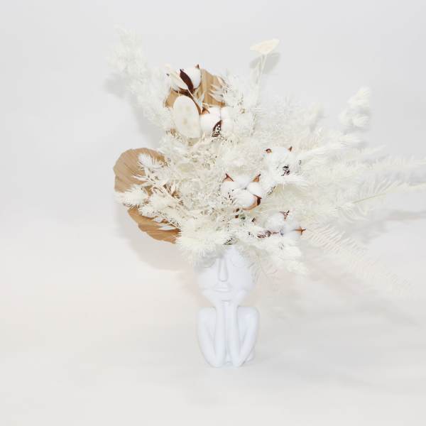 White floral arrangement in a white face-shaped vase