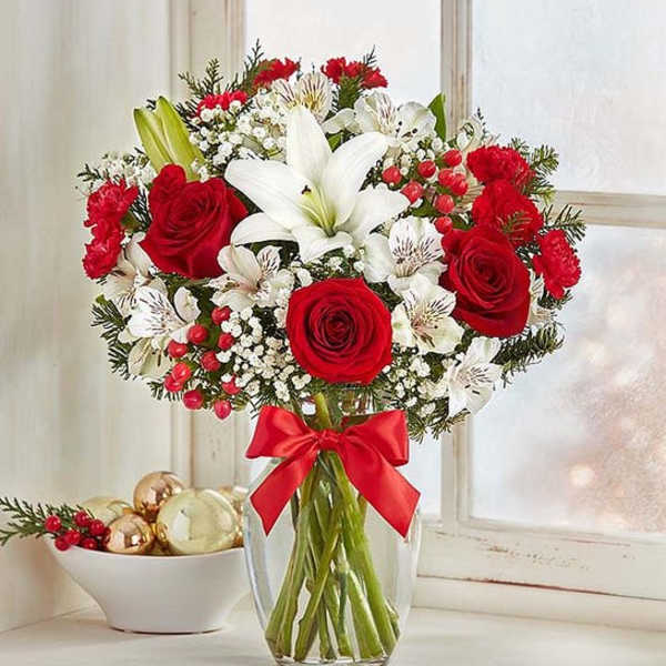 Red roses and white lilies in a glass vase with a red ribbon