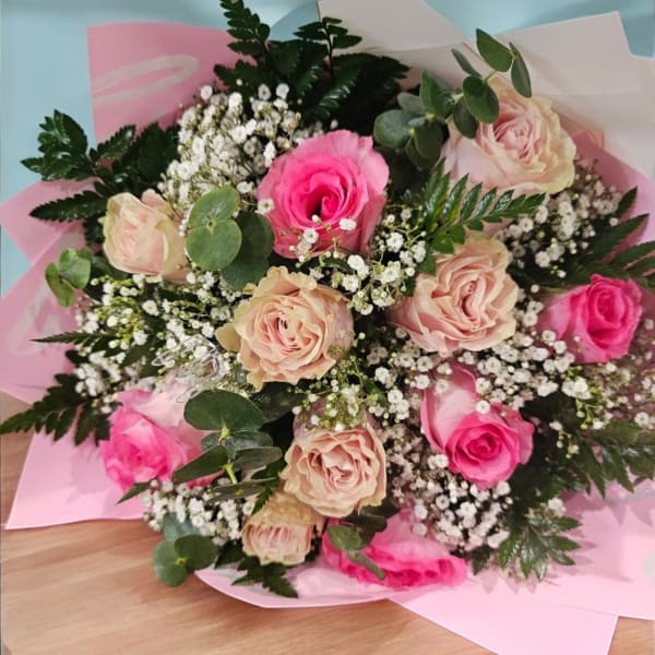 Bouquet of pink and blush roses with baby's breath in pink wrapping