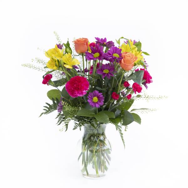 Mixed bouquet of roses, daisies, and carnations in a clear glass vase