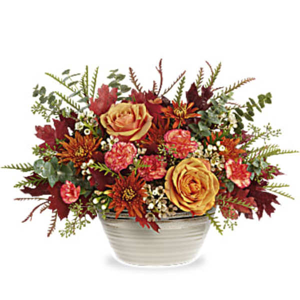 Autumn floral arrangement in a white ceramic bowl with orange and red blooms