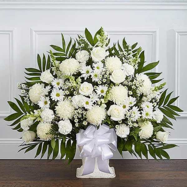 White floral standing arrangement with a white ribbon on a pedestal base