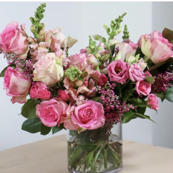 Pink roses and mixed blooms arranged in a clear glass vase