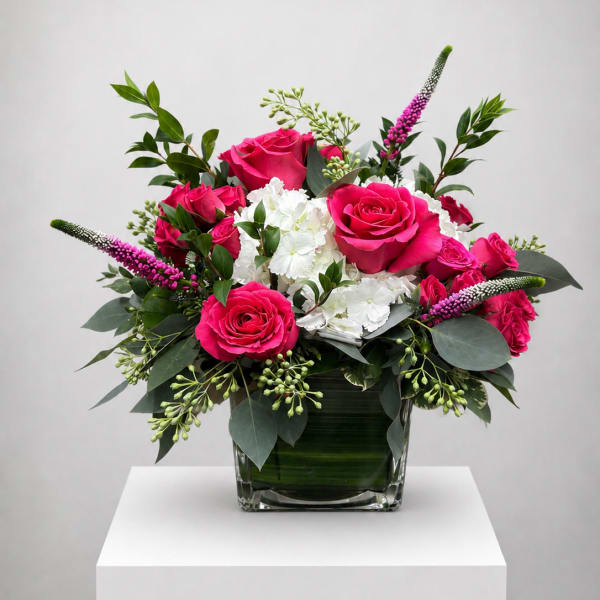 Pink roses and white hydrangeas in a glass vase with greenery