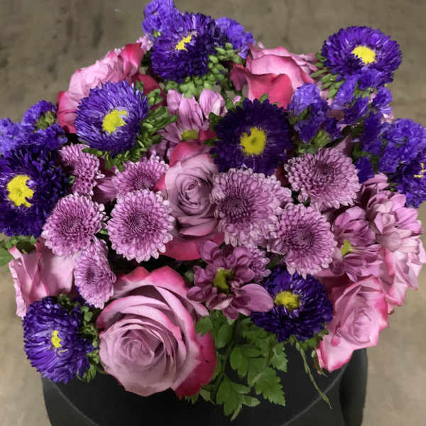 Bouquet of pink roses and purple daisies in a black wrap