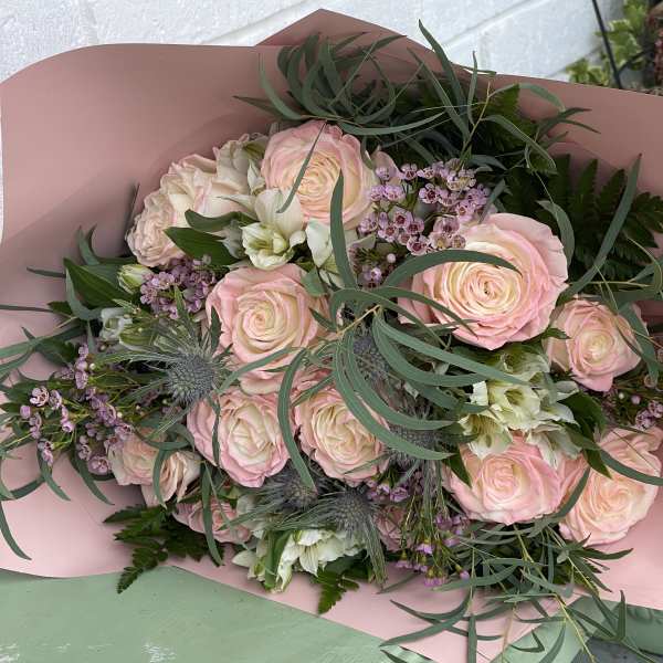 Bouquet of pale pink roses with small purple flowers and greenery