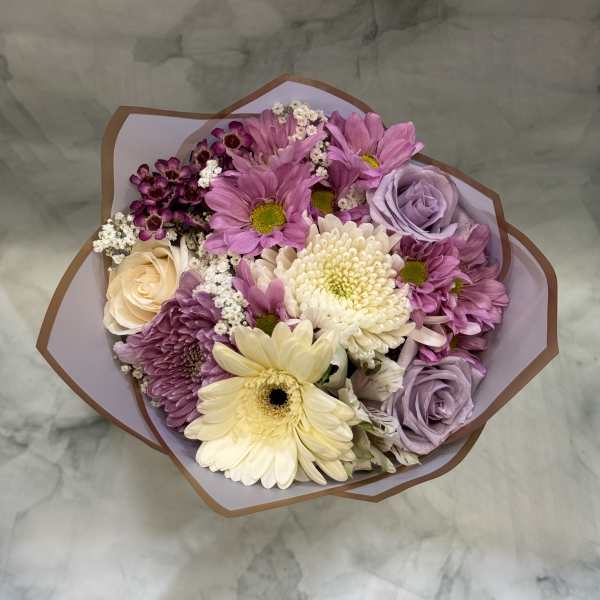 Bouquet of pink and lavender flowers with cream blooms in paper wrap