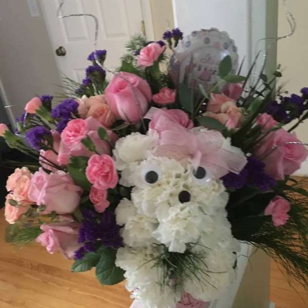 Pink and white floral arrangement with a teddy bear centerpiece