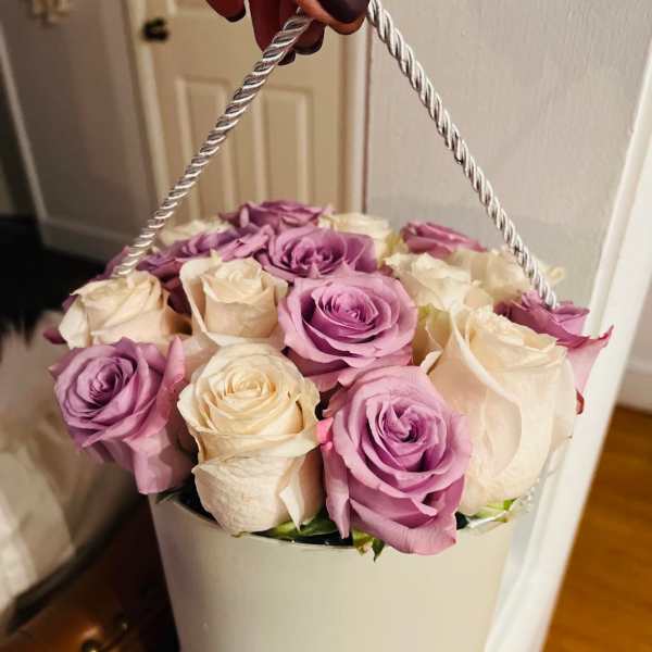 Lavender and cream roses arranged in a white hatbox with a rope handle