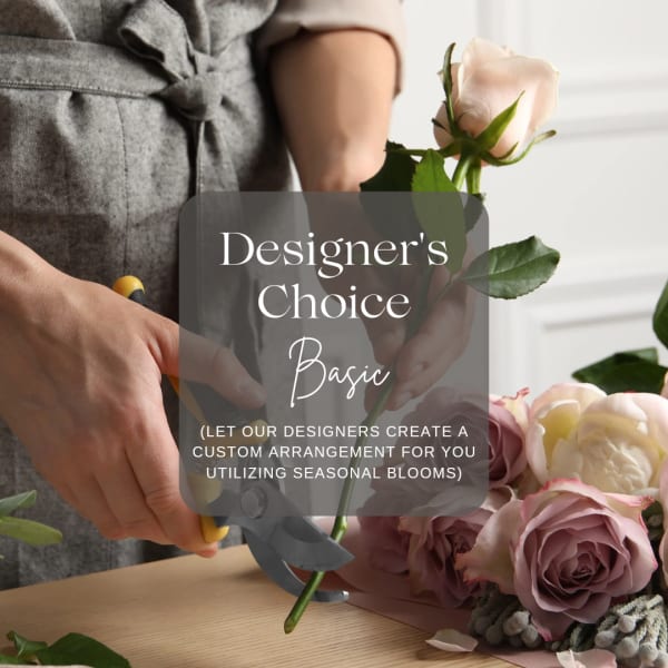 Hands trimming pale pink roses beside a floral arrangement